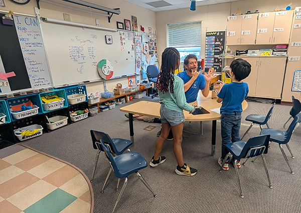 Paul Ososki, now in his 14th year as a kindergarten teacher at the Kansas School for the Deaf, works with two of his students during the Kansas State Board of Education's visit to the Olathe school in April.